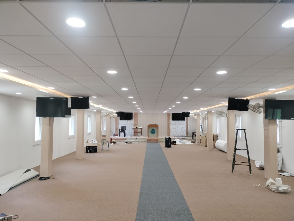 Large commercial hall with grid false ceiling, recessed downlights and cove lighting