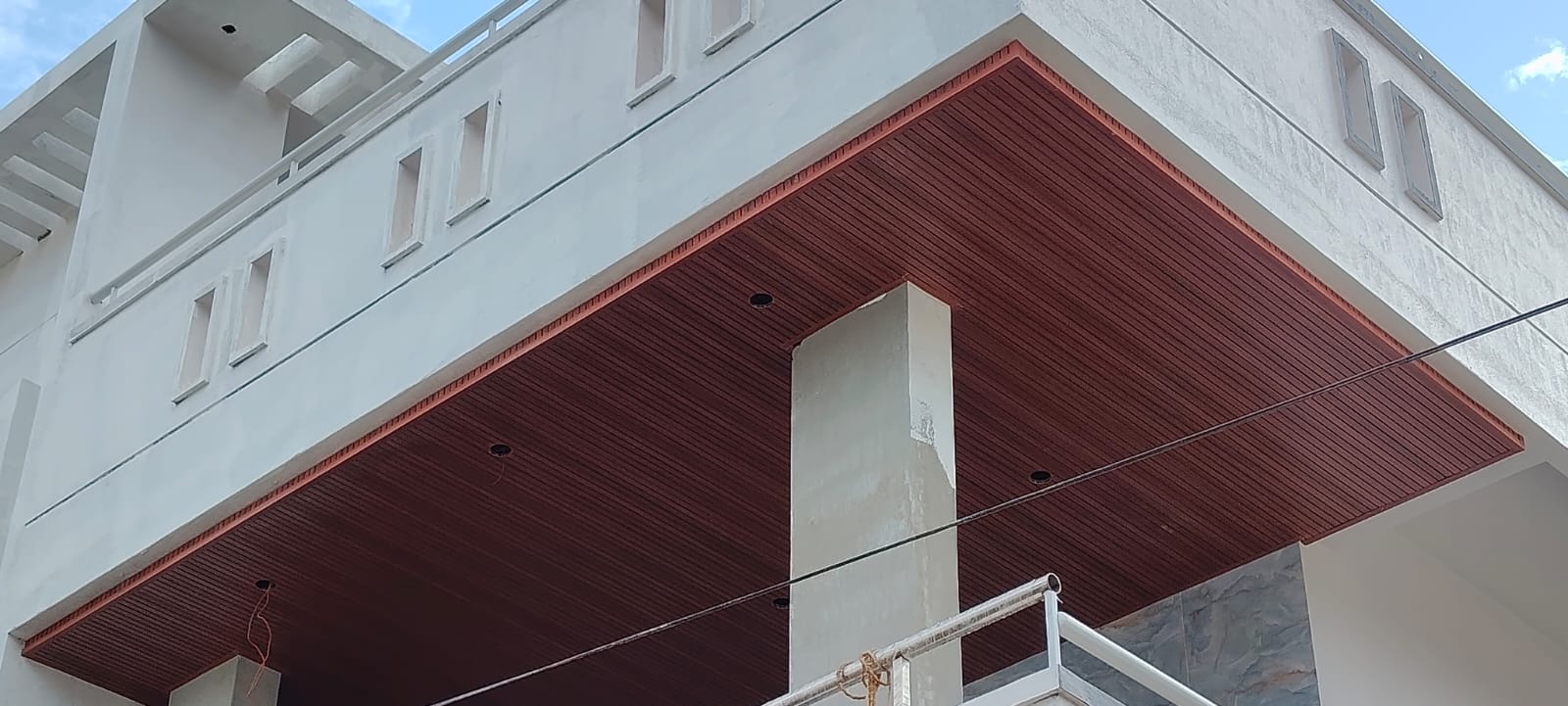 Exterior porch soffit finished with dark wooden louvre panelling and light cutouts